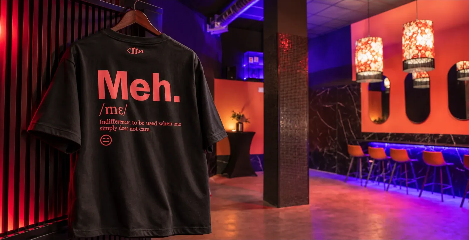 Camiseta MEH. colgada en un bar con luces rojas y violetas